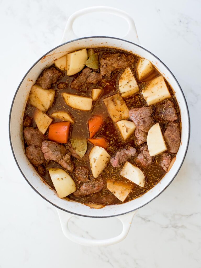 simple beef stew recipe in a dutch oven about to be simmered on the stove