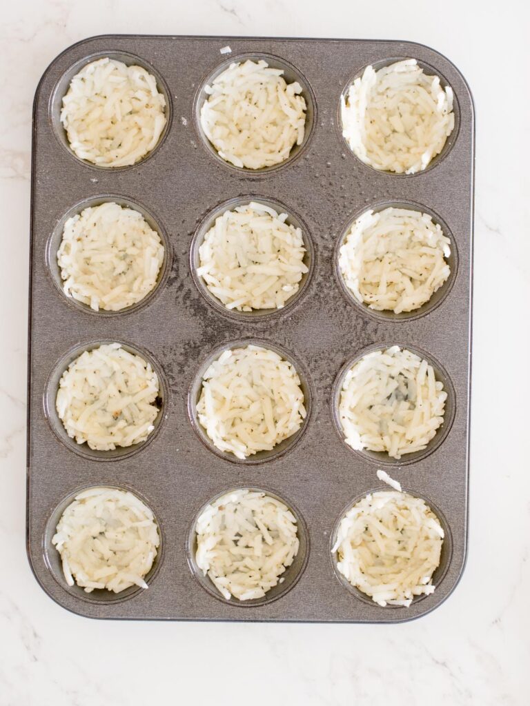 seasoned hashbrowns pushed and shaped into a muffin tin