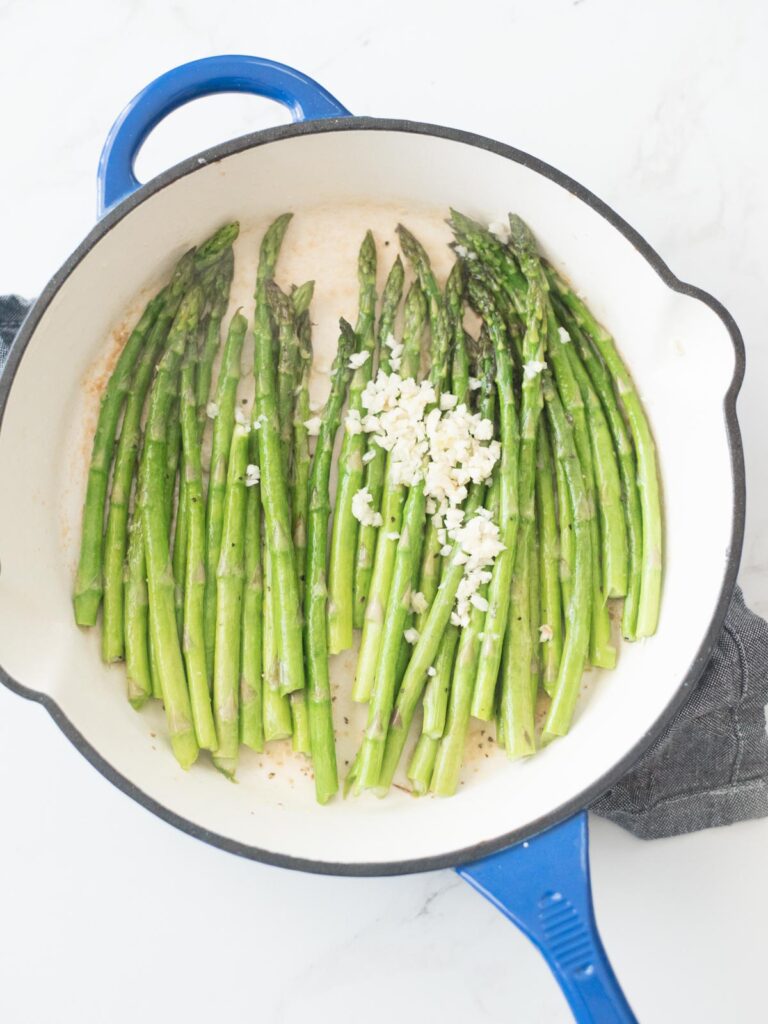 garlic added to cast iron skillet with butter asparagus