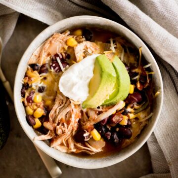 mexican chili topped with sour cream and avocado in a bowl