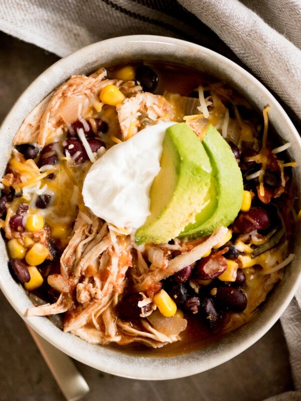 mexican chili topped with sour cream and avocado in a bowl