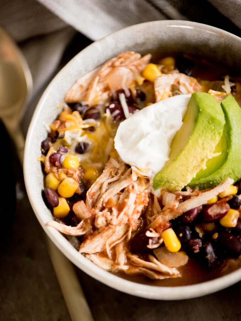 mexican chili in a bowl topped with sour cream and avocado