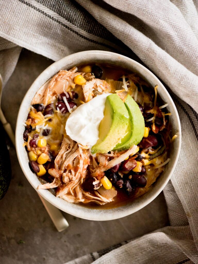 mexican chili in a bowl topped with sour cream and avocado