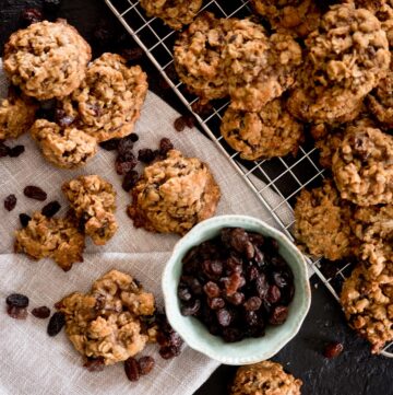 oatmeal raisin cookies stacked on a cooling rack with extra raisins