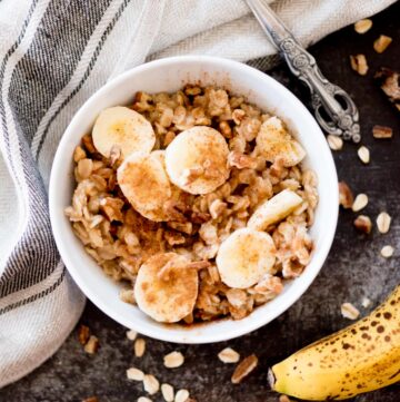 banana oatmeal in a bowl topped with cinnamon and nuts