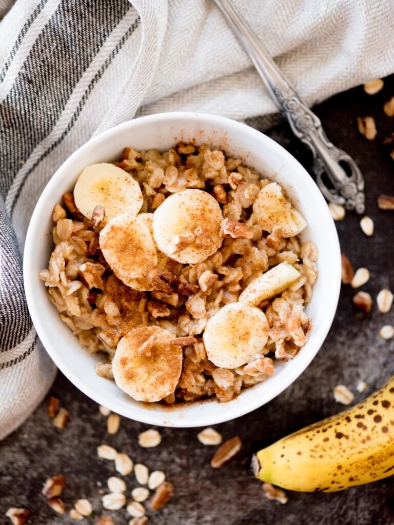 banana oatmeal in a bowl topped with nuts and cinnamon