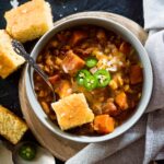 crockpot chicken chili in a bowl topped with cornbread and jalapenos