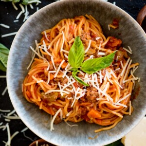 instant pot spaghetti in a bowl topped with fresh basil and parmesan cheese