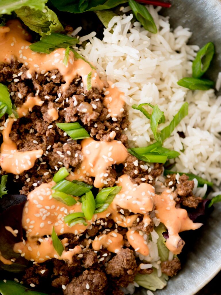 korean beef bowls topped with spicy mayo and sesame seeds