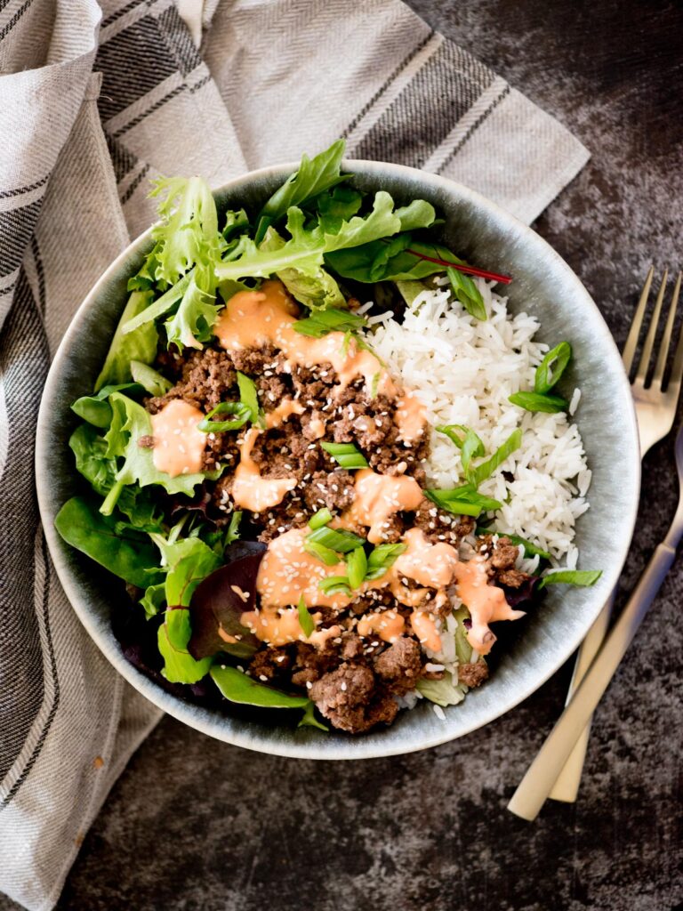 korean beef bowls topped with spicy mayo and sesame seeds