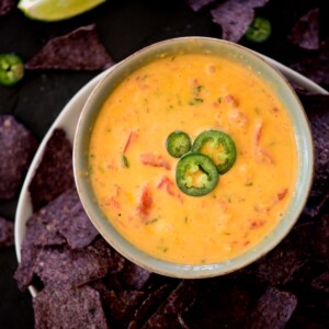 smoked queso in a bowl topped with sliced jalapenos and chips