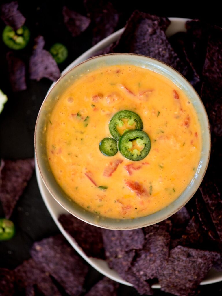 smoked queso dip in a bowl topped with jalapeno slices and surrounded by chips
