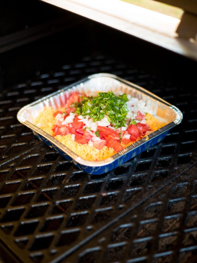 smoked queso dip ingredients in disposable aluminum pan placed on smoker