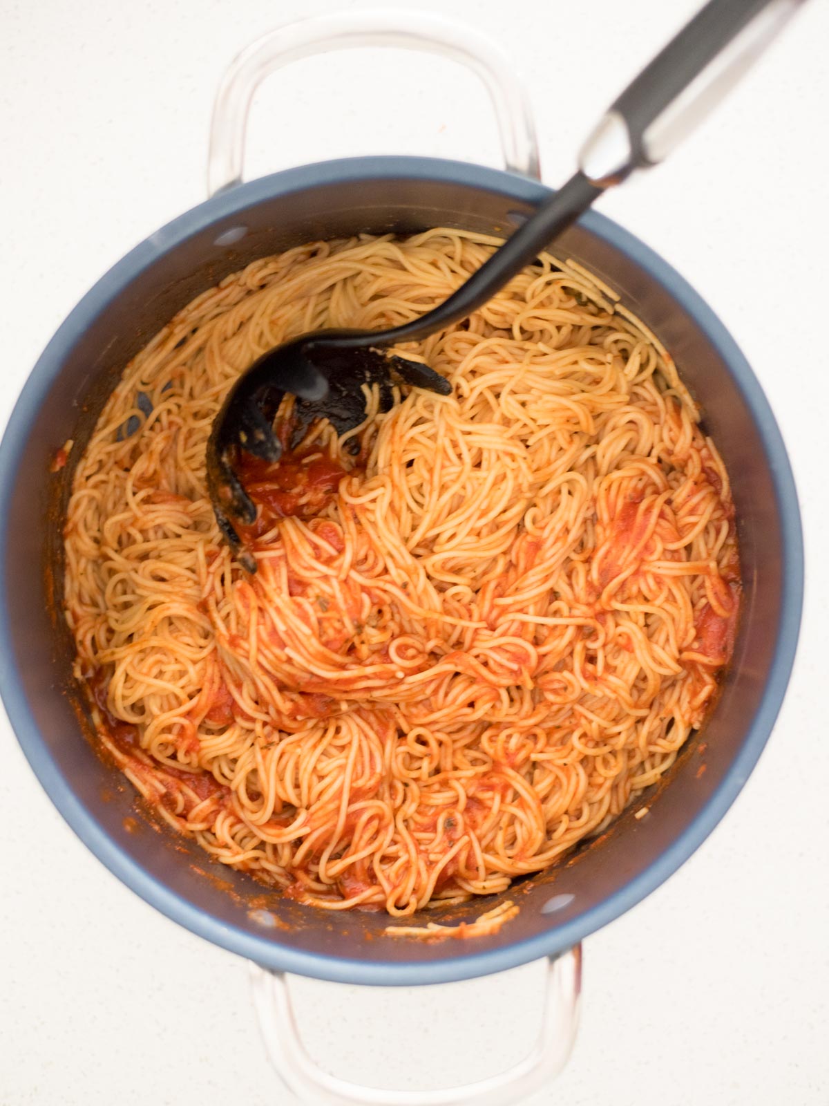 cooked spaghetti noodles and marinara mixed together in a pot