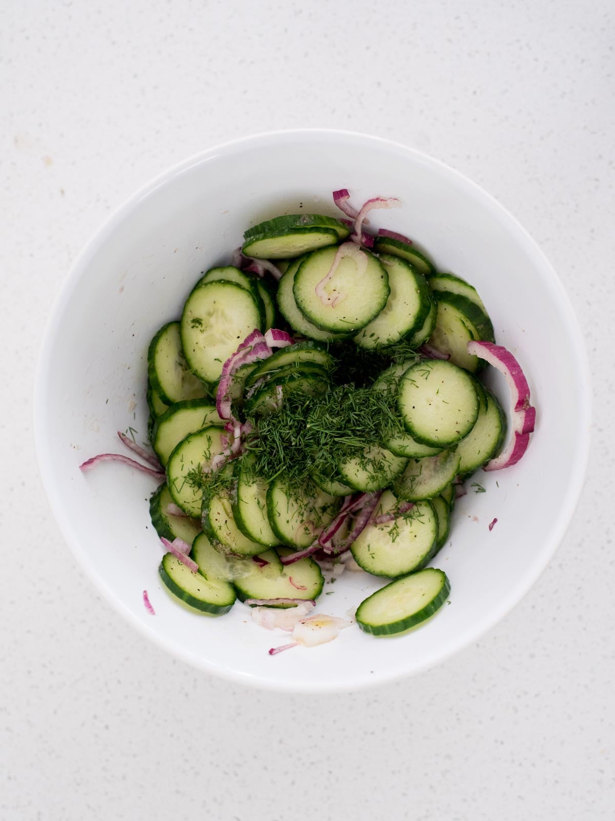 fresh dill added to the mixing bowl with onions and cucumbers
