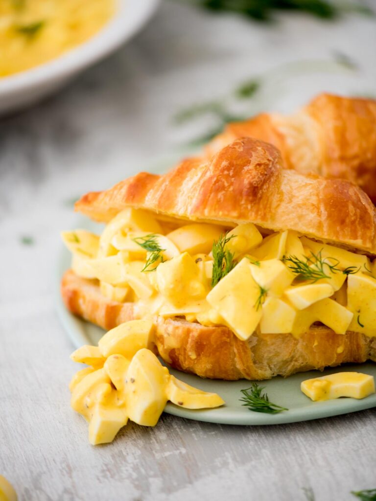 easy egg salad on a croissant topped with fresh dill