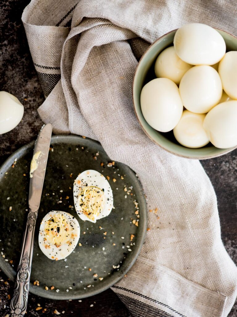 hard boiled eggs in a bowl with a sliced egg on a plate seasoned with everything seasoning