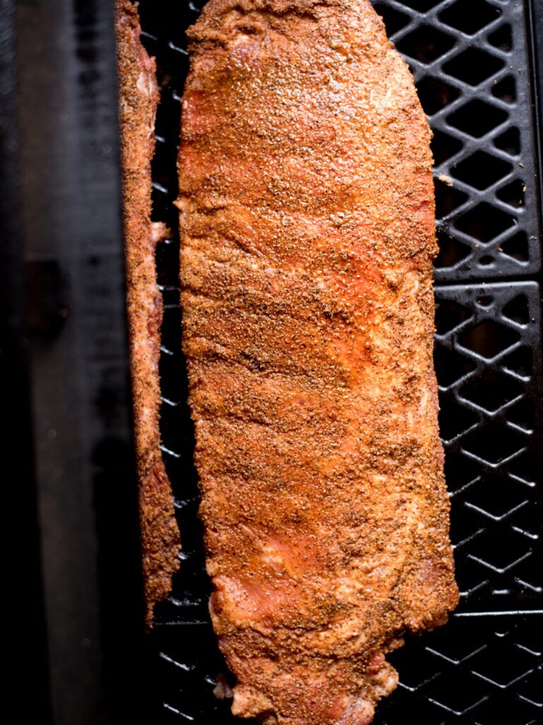 st louis style ribs covered in rub on a smoker