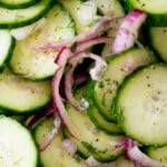 Sliced cucumbers and red onions are mixed with dill in tangy vinegar, creating a refreshing bowl of cucumbers and onions in vinegar, as shown with a label that reads, “cucumbers & onion in vinegar.”.