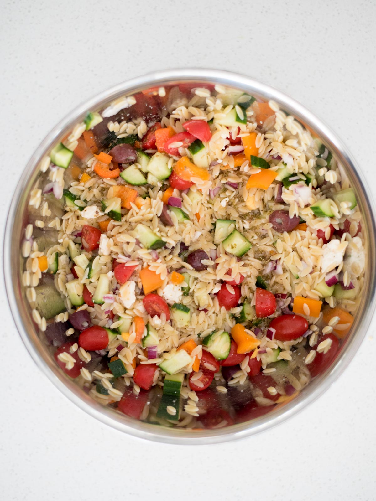 dressing added to the mixing bowl with the vegetables and orzo