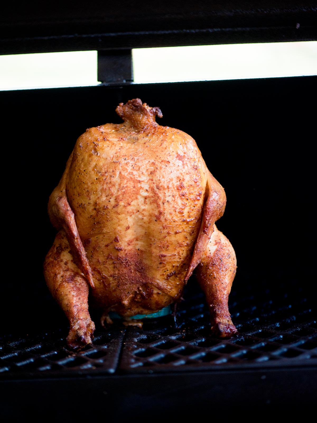 fully cooked beer can smoked chicken sitting on a pit boss grill