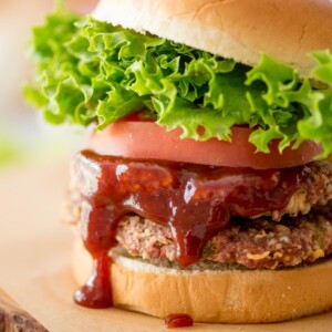 smoked burgers with bbq sauce, lettuce, and tomato on a butter bread bun