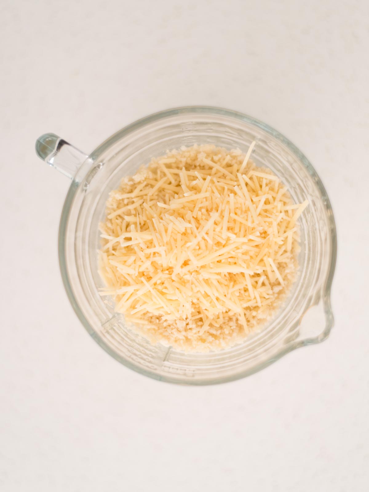 grated parmesan added to the buttered breadcrumbs in a measuring cup