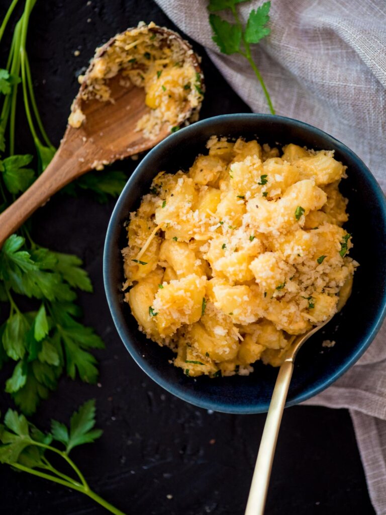 smoked mac n cheese in a blue bowl with a fork surrounded by parsley