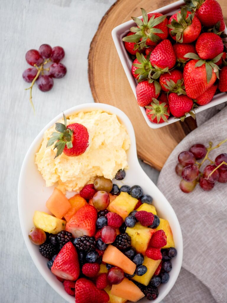 yogurt fruit dip with a bowl of fruit and a container of strawberries