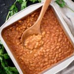 smoked baked beans in a baking dish with a spoon