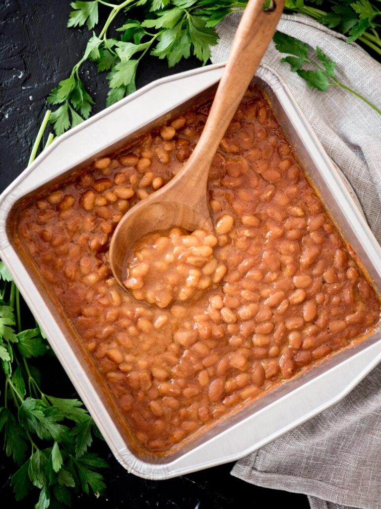smoked baked beans in a container with a spoon