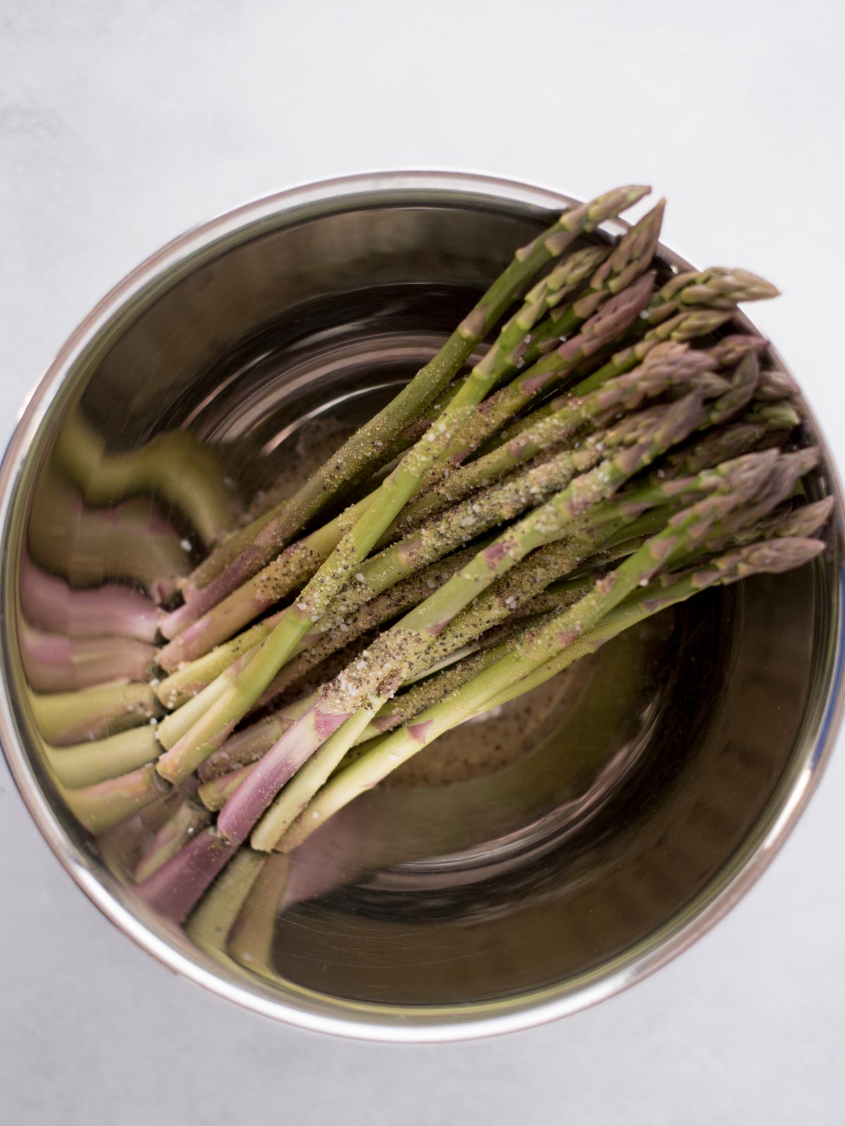 Seasoned asparagus in a mixing bowl.