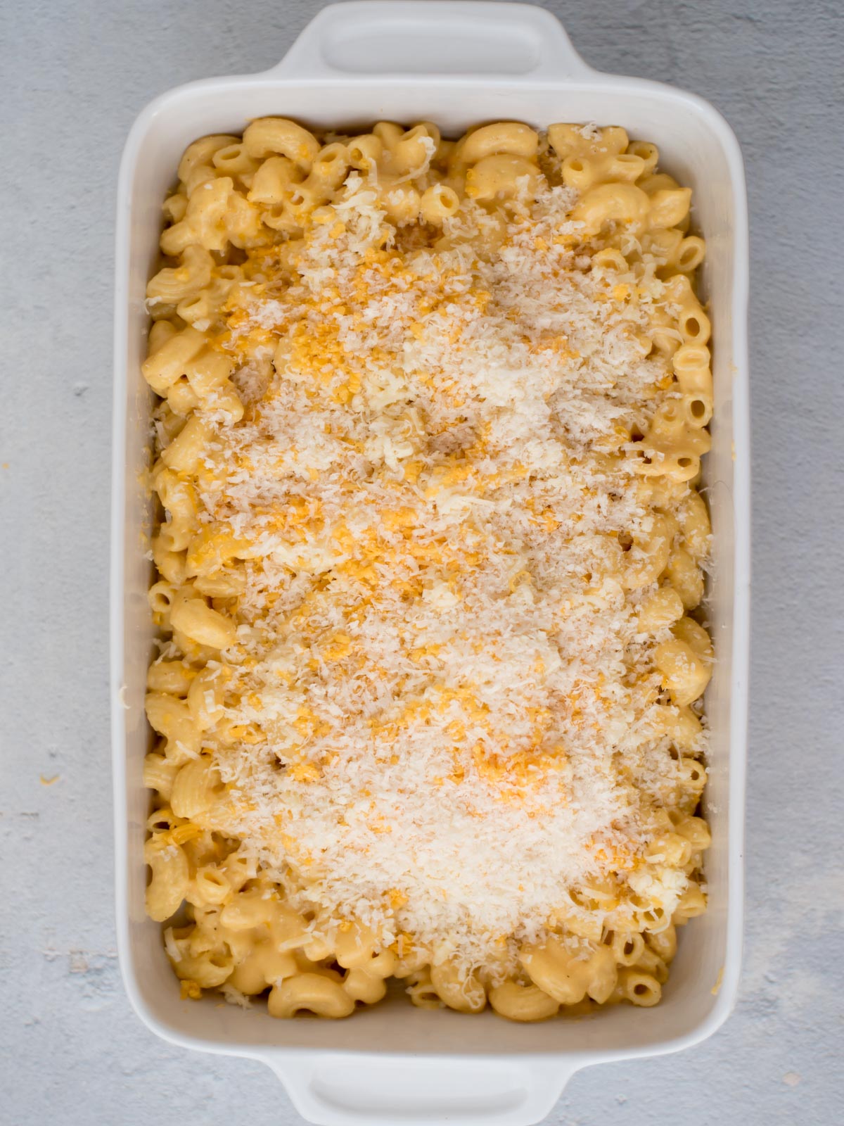 Mac and cheese in a baking dish with shredded cheese sprinkled on top.