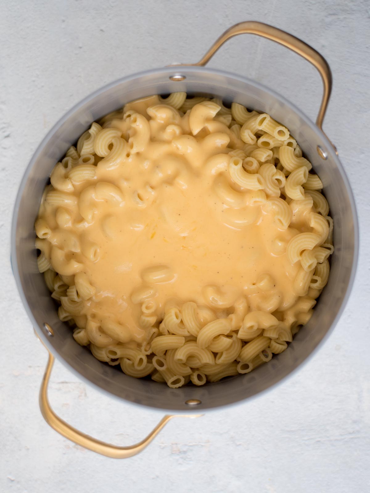 Cheese sauce placed over cooked pasta in a saucepan.