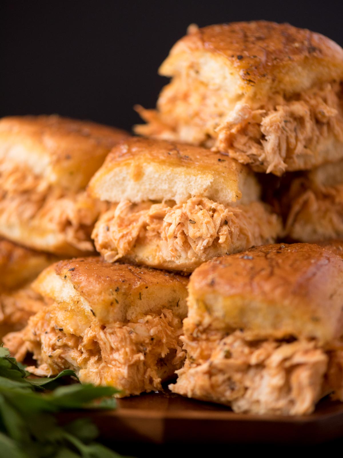 Buffalo chicken sliders stacked on top of one another on a plate.