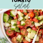 Bowl of salad with a serving spoon tucked into it with text overlay cucumber tomato salad.