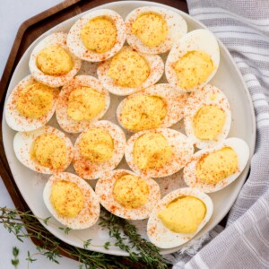 Paprika sprinkled deviled eggs served on a white plate.