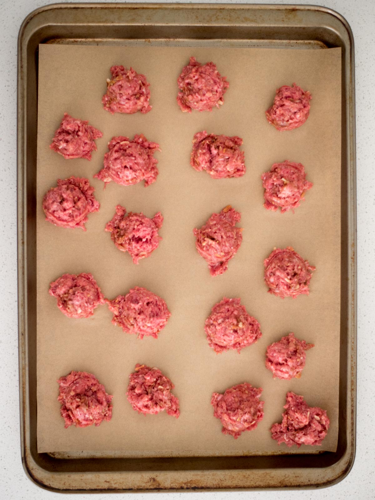meatballs scooped on to a parchment lined baking sheet