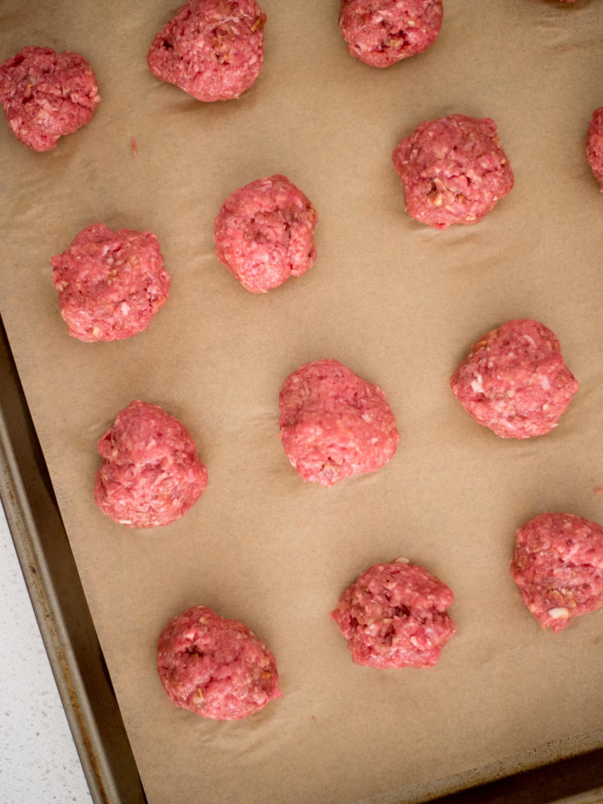 meatballs formed into smooth balls on a parchment lined baking sheet