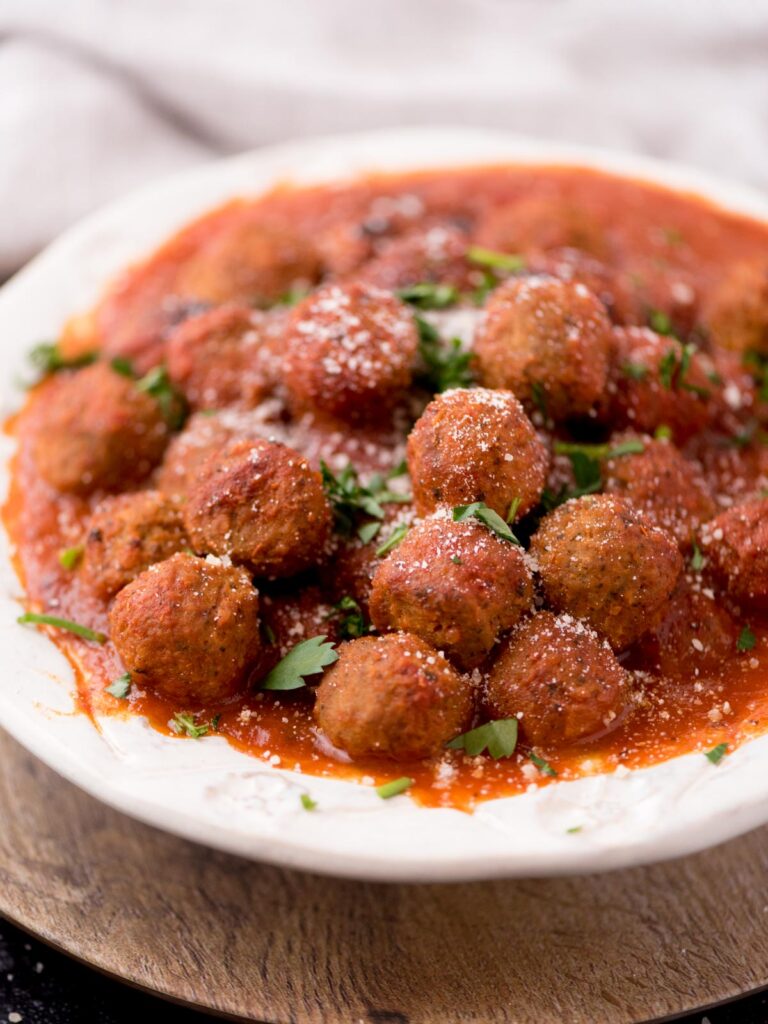 Sauce covered meatballs in a serving bowl.