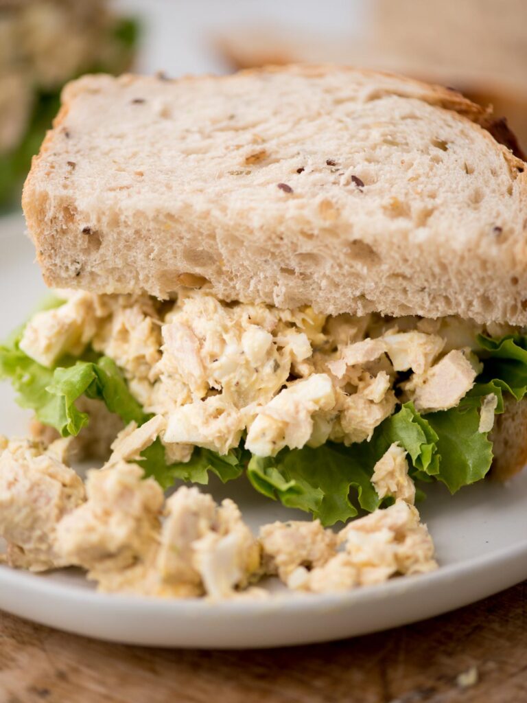 Close up of a half tuna salad sandwich served on a plate.