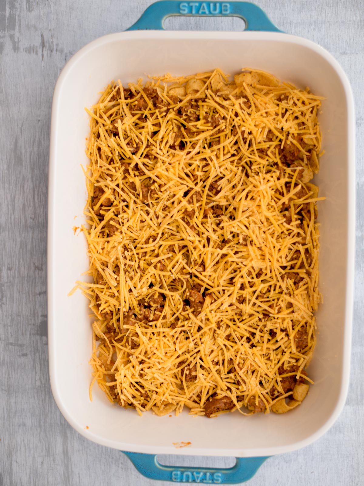 Shredded cheese topped over the fritos and seasoned ground beef.