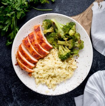 Sliced smoked chicken breasts plated with broccoli and rice.