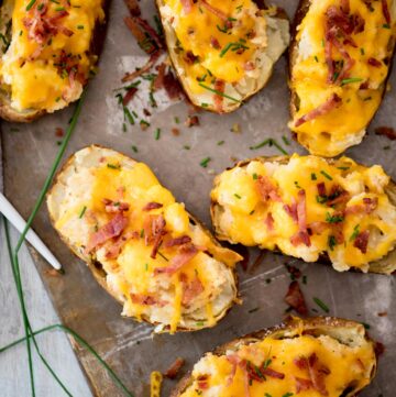 Twice baked potatoes topped with extra bacon sitting on a baking sheet.