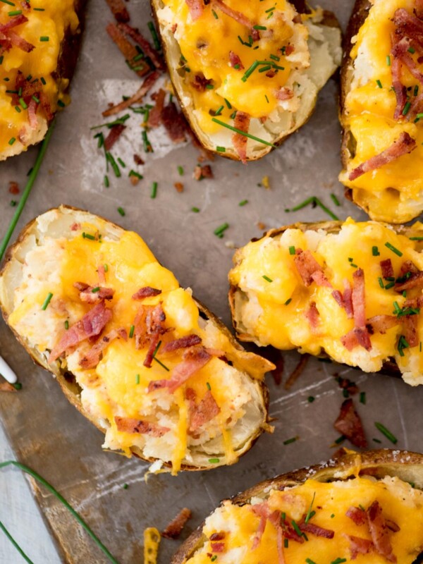 Twice baked potatoes topped with extra bacon sitting on a baking sheet.