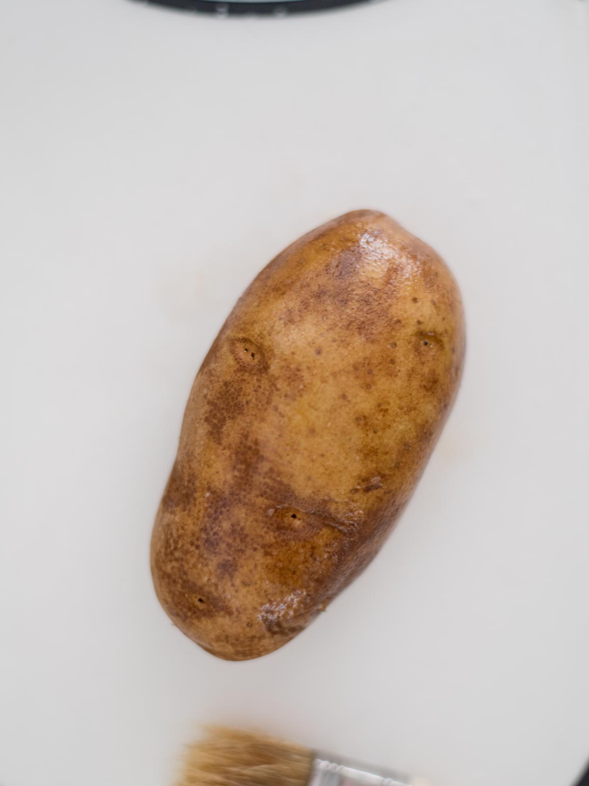 A washed whole potato poked with the tines of a fork.