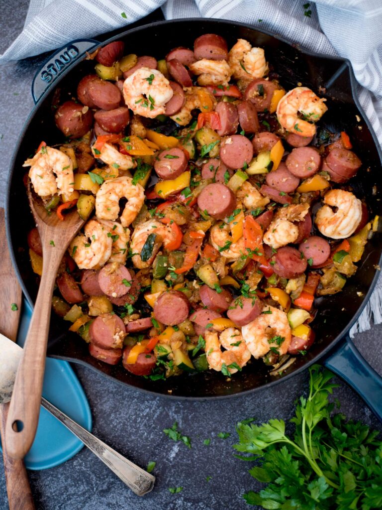 Top view of a cast iron pan with cajun shrimp, sausage and vegetables