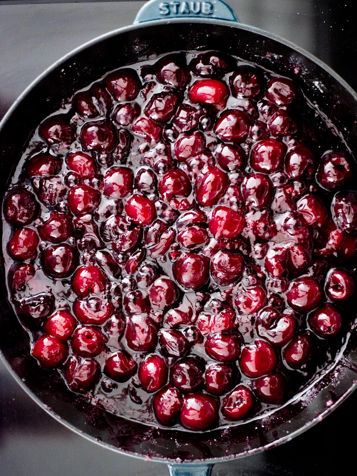 cherries cooked down in a cast iron skillet on the stove