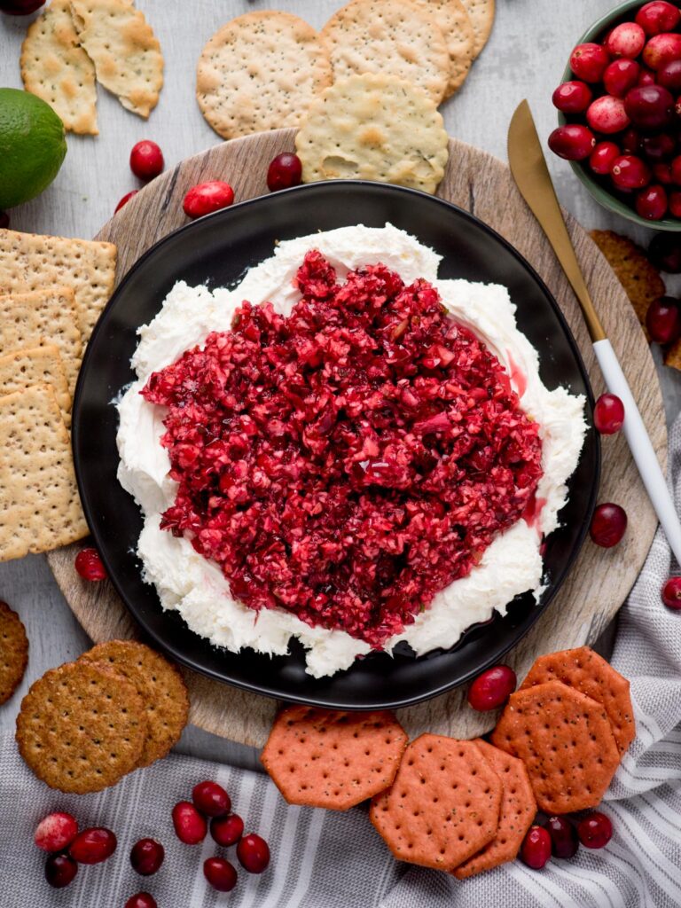 Top view of whipped cream cheese cranberry jalapeno dip with a variety of crackers served around it.
