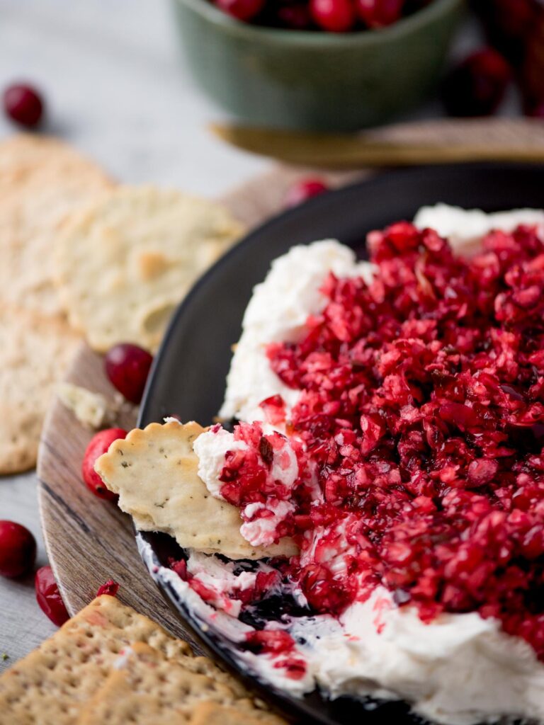 Cranberry jalapeno dip served over whipped cream cheese and crackers served around it.